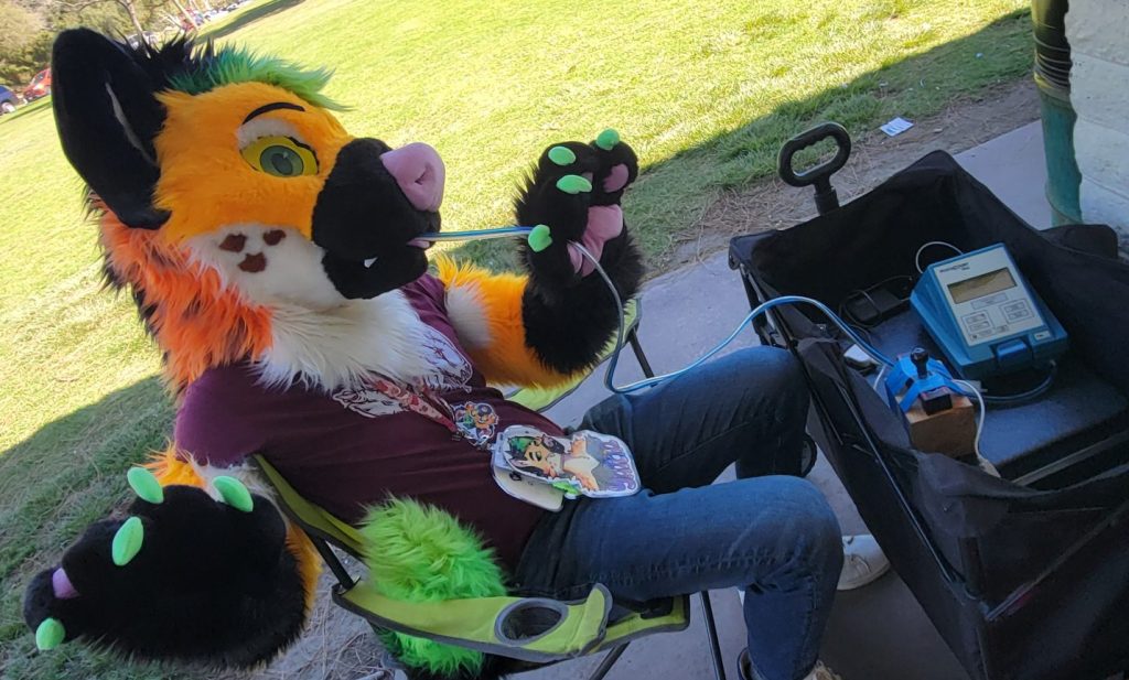 A fursuiter taking a mask fit test using a PortaCount fit testing machine.
